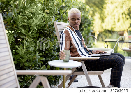 Latin man using laptop on lounger at house garden 83703055