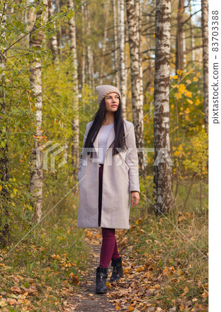 Portrait of a joyful young woman enjoying in the autumn park. 83703388