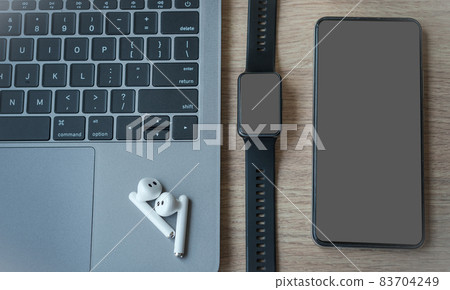 Close-up of Keyboard laptop computer, wireless earphones focus with smartwatch and smartphone empty screen on wooden background office desk in coffee shop like the background Close-up of Keyboard laptop computer, wireless earphones focus with smartwatch and smartphone empty screen on wooden background office desk in coffee shop like the background 83704249