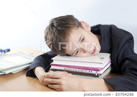 Schoolboy put his head on a stack of books Schoolboy put his head on a stack of books 83704286