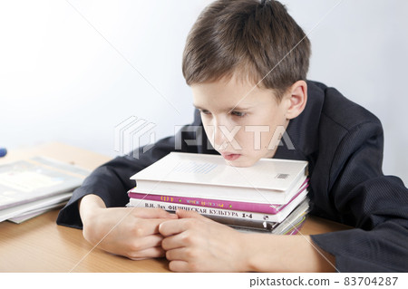 Tired, thoughtful student with a stack of books 83704287