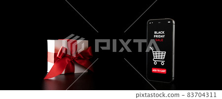 Black Friday banner with internet online shopping app on mobile phone, white gifts with red bow falling on black discount background. Black Friday banner with internet online shopping app on mobile phone, white gifts with red bow falling on black discount background. 83704311