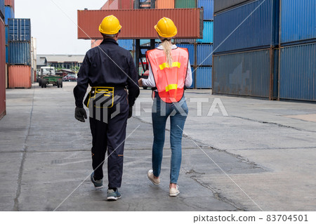 Industrial worker works with co-worker at overseas shipping container yard 83704501