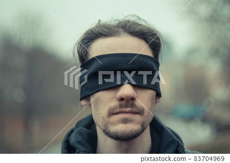 a man with a black blindfold over his eyes a man with a black blindfold over his eyes 83704969
