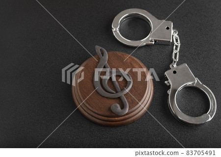 Treble clef sign and handcuffs. Illegal use of someone elses music. Copyright infringement. Music Licensing. 83705491