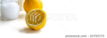 A lemon cut in half in the foreground, a glass jar with a moisturizer or balm in the background. Concept: cosmetics, body and hair care, spa, proper nutrition, vitamins, medicine. 83705575