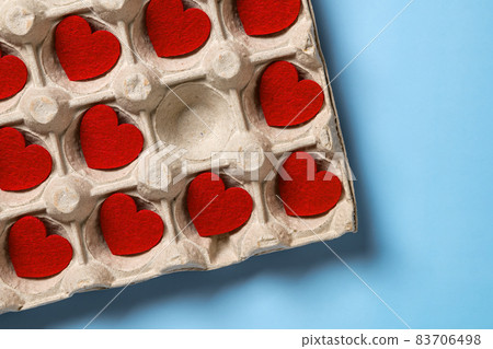 Several Valentine hearts in the cardboard tray over blue background. Concepts of heartbreaker. Several Valentine hearts in the cardboard tray over blue background. Concepts of heartbreaker. 83706498