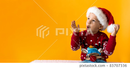 Portrait of happy smiling positive joyful positive preschool little boy in red warm santa hat showing thumb up on orange, yellow background. Winter, holiday, celebration, Christmas, New Year copy Portrait of happy smiling positive joyful positive preschool little boy in red warm santa hat showing thumb up on orange, yellow background. Winter, holiday, celebration, Christmas, New Year copy 83707336
