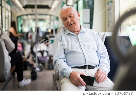 Elderly man sitting in tram and sleeping 83708757