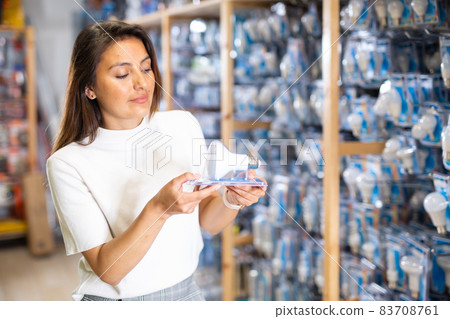 Cheerful woman buyers energy saving lamp at hardware store Cheerful woman buyers energy saving lamp at hardware store 83708761