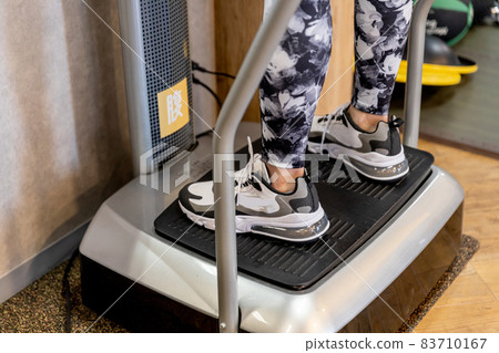 A woman using a vibrating machine in a gym 83710167