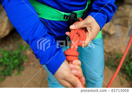 Rock climber making a eight knot 83713008