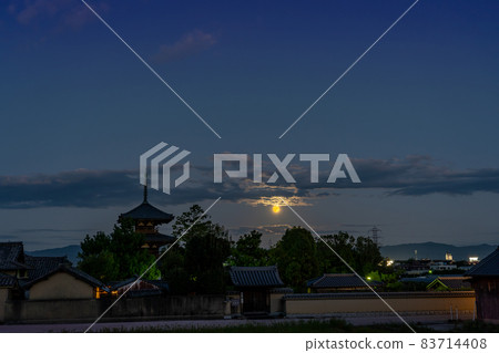 Ikaruga Town, Nara Prefecture, a harvest moon rising from the other side of the three-storied pagoda of Hokiji Temple, a World Heritage Site 83714408