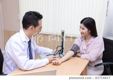 Doctor measures the pressure of the patient during a medical examination and discuss in the hospital. 83714657