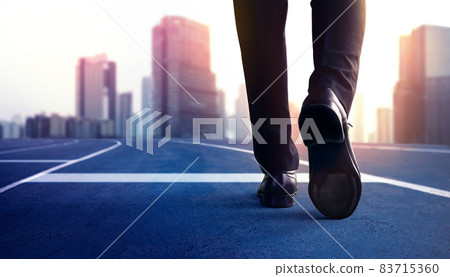 Start, Competition Concept. Low Section of Businessman Steps into Start Line on Running Track and Moving Forward to New Challenge. Blurred City Building as background Start, Competition Concept. Low Section of Businessman Steps into Start Line on Running Track and Moving Forward to New Challenge. Blurred City Building as background 83715360