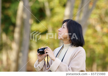 一位微笑的中年婦女在秋季公園拍照，上身 83715980