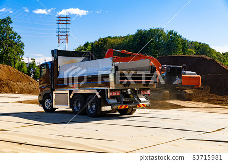 Construction site: Large dump truck, backhoe and blue sky Construction site: Large dump truck, backhoe and blue sky 83715981