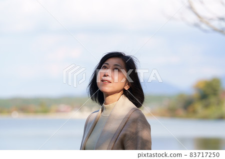 A middle-aged woman nestled on the shore of a lake 83717250