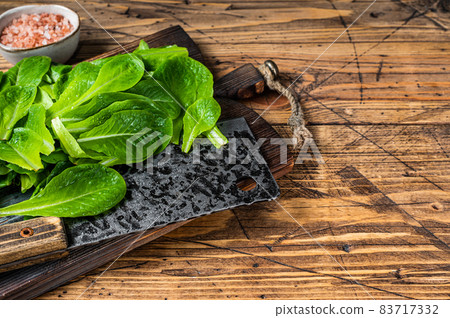 Baby romain green salad leaves on wooden cutting board. wooden background. Top view. Copy space Baby romain green salad leaves on wooden cutting board. wooden background. Top view. Copy space 83717332