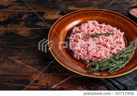 Ground chicken or turkey meat, raw Poultry on rustic plate with herbs. Dark background. Top View. Copy space 83717408
