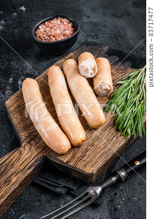 Roasted chicken and turkey sausages on a wooden board. Black background. Top view 83717477