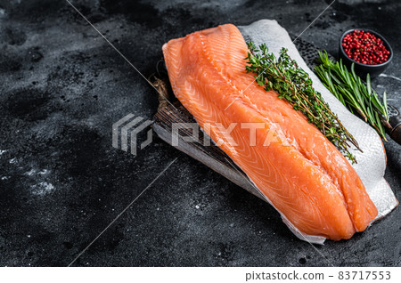 Fresh raw salmon fillet fish on cutting board with knife. Black background. Top view. Copy space 83717553
