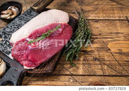 Fresh Raw Duck breast fillet steaks on butcher board with meat cleaver. wooden background. Top View. Copy space 83717828