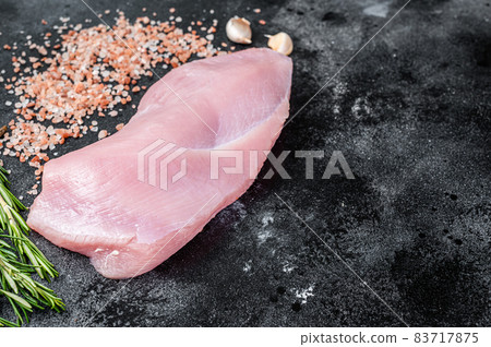 Raw Poultry turkey breast fillet meat on a butcher table with rosemary and salt. Black background. Top View. Copy space Raw Poultry turkey breast fillet meat on a butcher table with rosemary and salt. Black background. Top View. Copy space 83717875