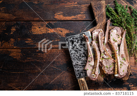 BBQ Grilled Lamb Ribs Chops steaks on butcher board with meat cleaver. Dark wooden background. Top view. Copy space BBQ Grilled Lamb Ribs Chops steaks on butcher board with meat cleaver. Dark wooden background. Top view. Copy space 83718115