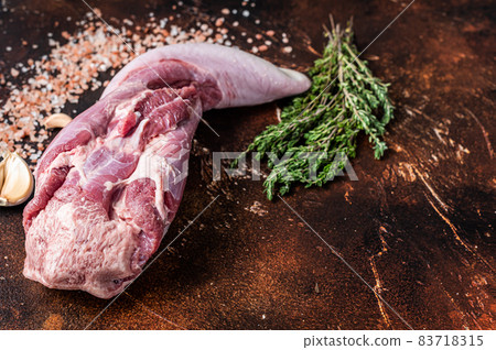 Raw beef tongue on kitchen table with herbs. Dark background. Top view. Copy space Raw beef tongue on kitchen table with herbs. Dark background. Top view. Copy space 83718315