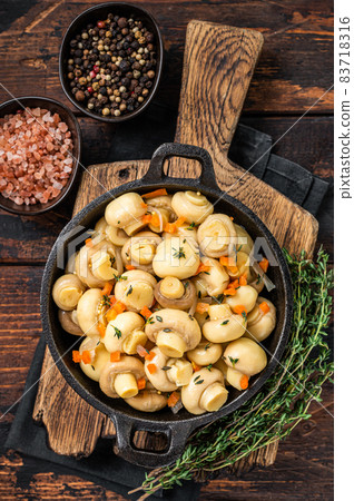 Marinated mushrooms champignons in a pan. Dark Wooden background. Top view 83718316