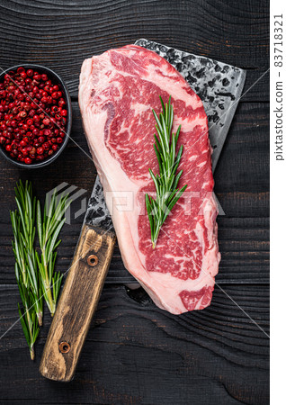 Fresh Raw striploin beef steak on a butcher meat cleaver. Black wooden background. Top view Fresh Raw striploin beef steak on a butcher meat cleaver. Black wooden background. Top view 83718321