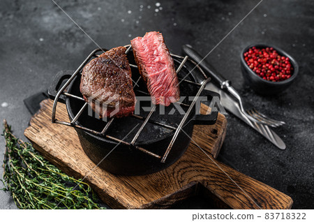 Beef tenderloin steak is grilled on a grill pan. Black background. Top view Beef tenderloin steak is grilled on a grill pan. Black background. Top view 83718322