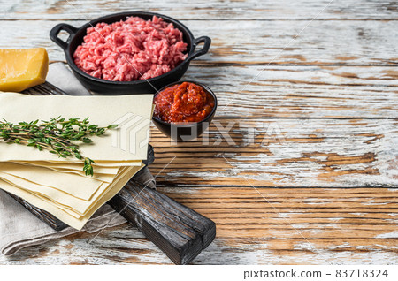 Lasagne raw sheets and other ingredients. White wooden background. Top view. Copy space Lasagne raw sheets and other ingredients. White wooden background. Top view. Copy space 83718324