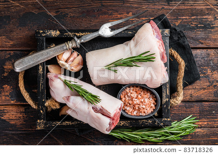 Uncooked Raw pork hoof, knuckle, feet in a wooden tray with herbs. Wooden background. Top view Uncooked Raw pork hoof, knuckle, feet in a wooden tray with herbs. Wooden background. Top view 83718326