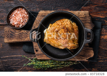 Baked chicken thigh in a pan with rosemary and salt. Dark wooden background. Top View 83718328