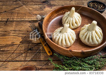 Boiled Khinkali Dumplings with mutton lamb meat in wooden plate. wooden background. Top view. Copy space Boiled Khinkali Dumplings with mutton lamb meat in wooden plate. wooden background. Top view. Copy space 83718330