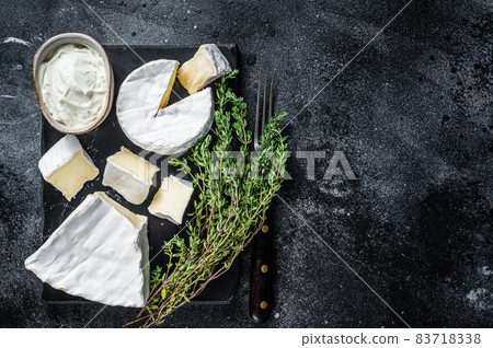 Cheese platter. Camembert, Brie, Gorgonzola and blue cream cheese with thyme. Black background. Top view. Copy space 83718338