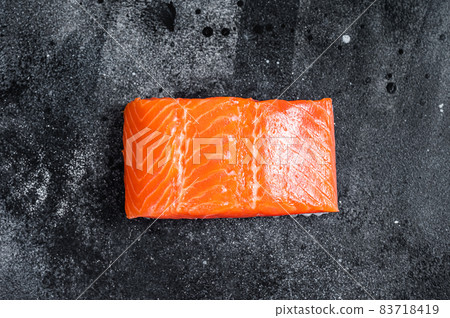 Raw salmon fillet steaks on kitchen table. Black background. Top view 83718419