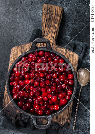 Red fresh Cranberry berry in a pan. Black background. Top view Red fresh Cranberry berry in a pan. Black background. Top view 83718452