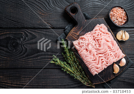 Fresh Raw mince or ground chicken meat on wooden chopping board with thyme. Black wooden background. Top view. Copy space Fresh Raw mince or ground chicken meat on wooden chopping board with thyme. Black wooden background. Top view. Copy space 83718453