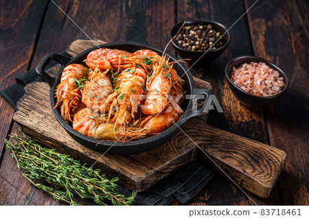 Cooking Greenland Shrimps Prawns in a pan with thyme and rosemary. Dark wooden background. Top view 83718461