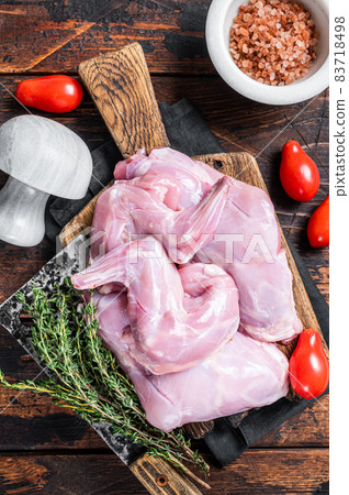 Raw hare legs on a butcher board with thyme. Dark wooden background. Top view Raw hare legs on a butcher board with thyme. Dark wooden background. Top view 83718498