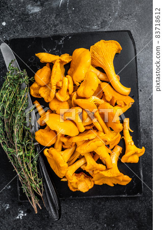 Raw wild Chanterelles mushrooms on a marble board. Black background. Top view 83718612