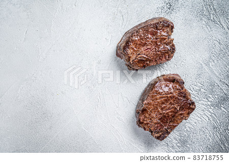 Grilled fillet mignon or tenderloin beef steak on kitchen table. White background. Top view. Copy space Grilled fillet mignon or tenderloin beef steak on kitchen table. White background. Top view. Copy space 83718755