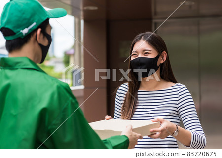 Woman with face mask take pizza from driveryman Woman with face mask take pizza from driveryman 83720675