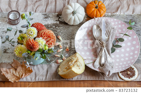 Festive table setting with pumpkins, candles and chrysanthemum flowers. 83723132