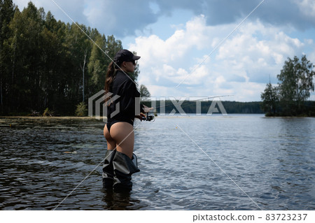 Sexy female fisher standing in lake 83723237