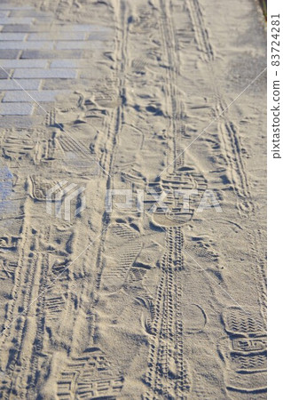 Footprints and tire marks left on the sand on the sidewalk Footprints and tire marks left on the sand on the sidewalk 83724281