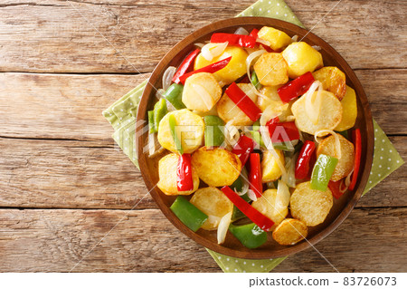 Patatas a lo pobre is a simple potato dish from Andalusian cuisine made of sliced potatoes are fried in olive oil with onion and peppers close up on the table. Horizontal top view Patatas a lo pobre is a simple potato dish from Andalusian cuisine made of sliced potatoes are fried in olive oil with onion and peppers close up on the table. Horizontal top view 83726073